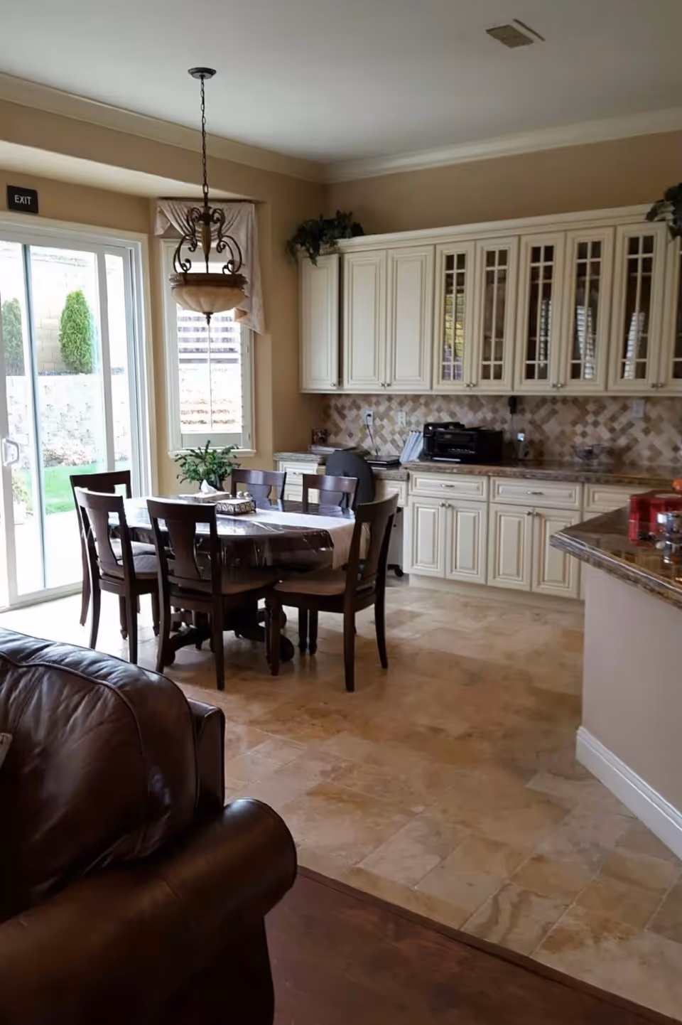 Bright kitchen-dining area with a round wooden table and chairs, cream cabinets, and a sliding glass door letting in daylight.