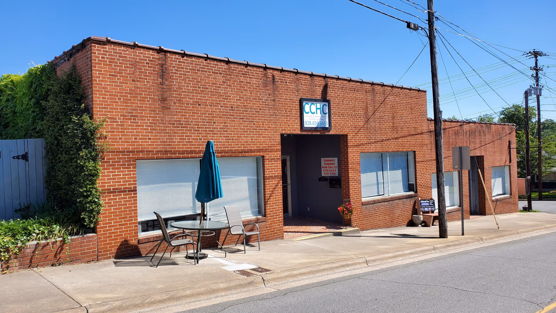 Brick building with outdoor seating along the sidewalk and blue sky above.