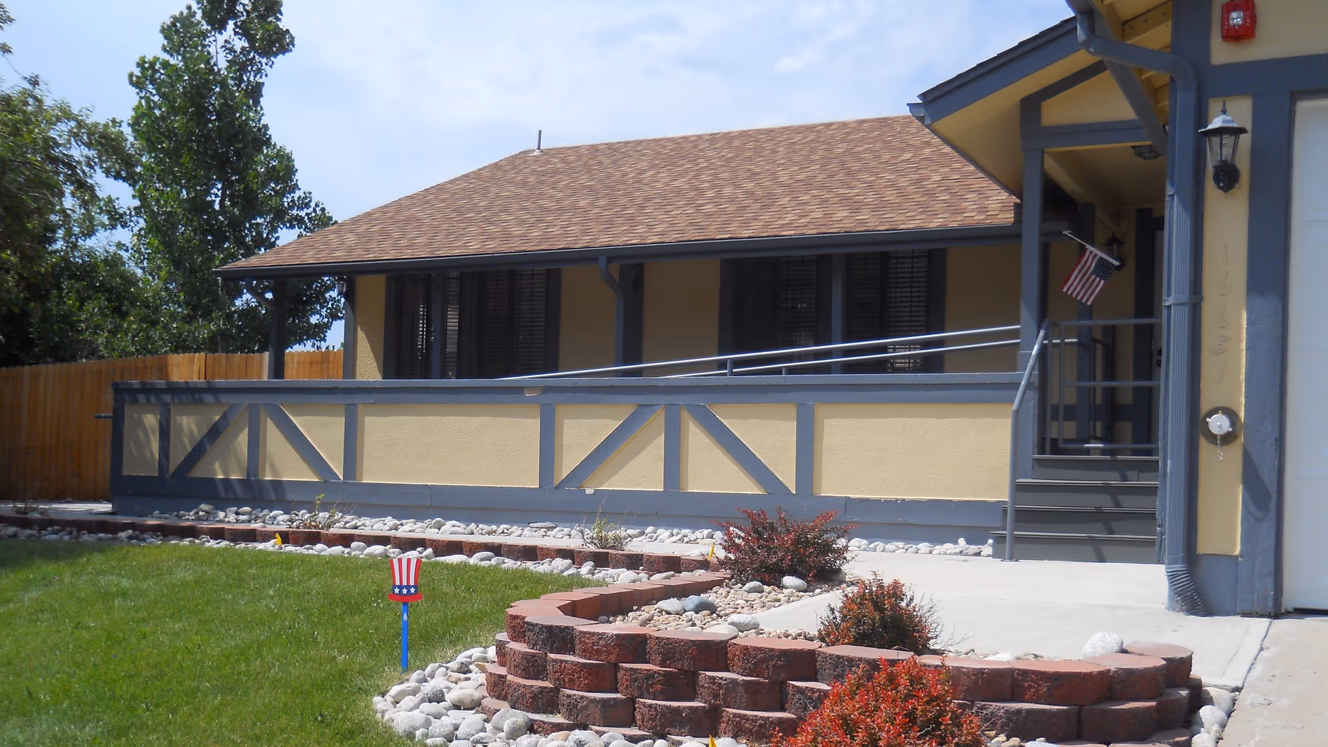Front view of a single-story assisted living facility with beige walls, blue trim, and a porch.
