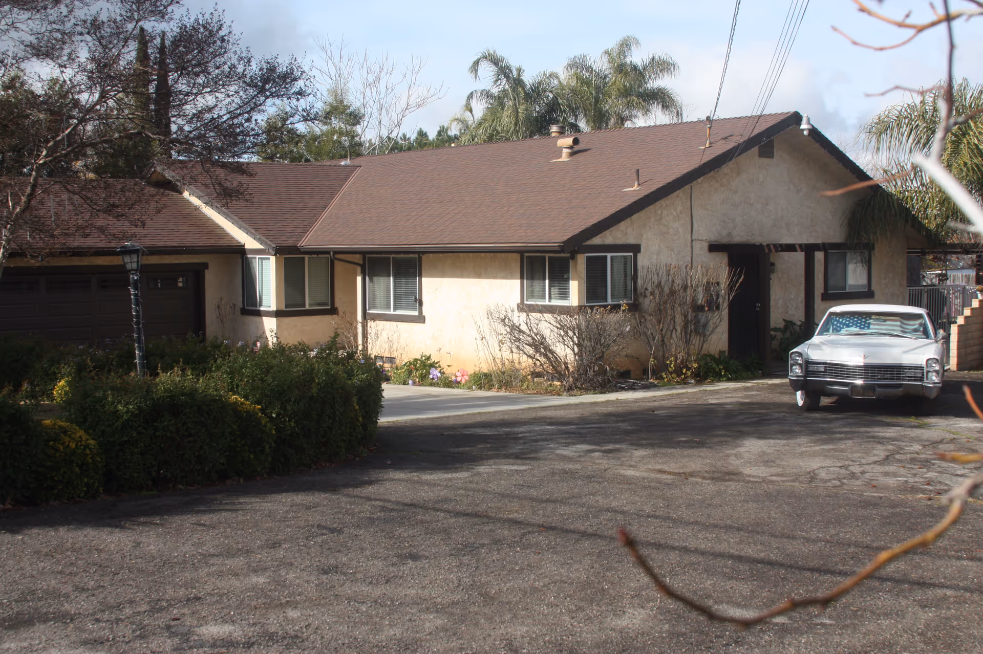 Exterior view of a single-story beige facility with a driveway and parked car.