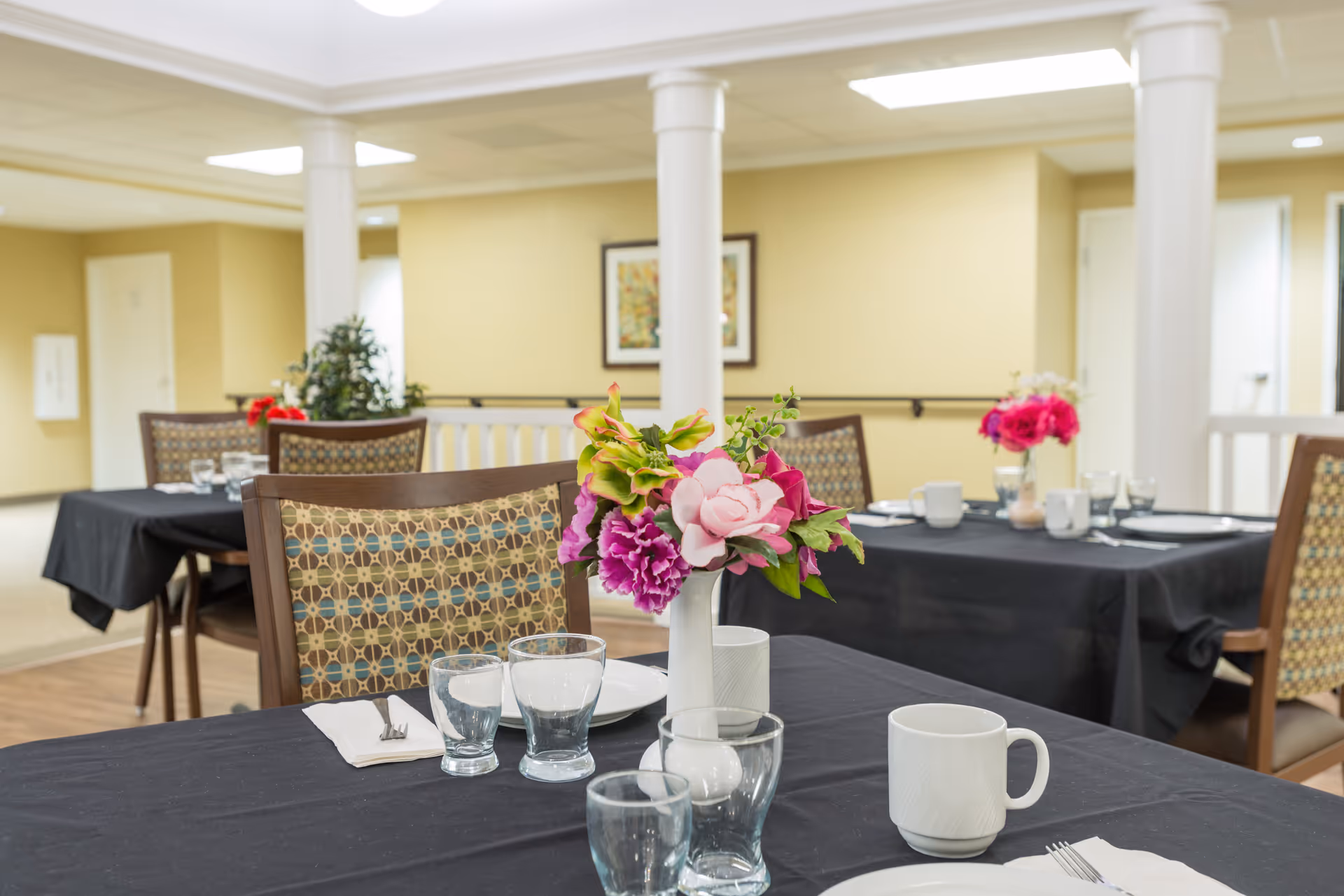 Interior dining room at Eagle Creek Nursing Center with tables set and floral centerpieces.