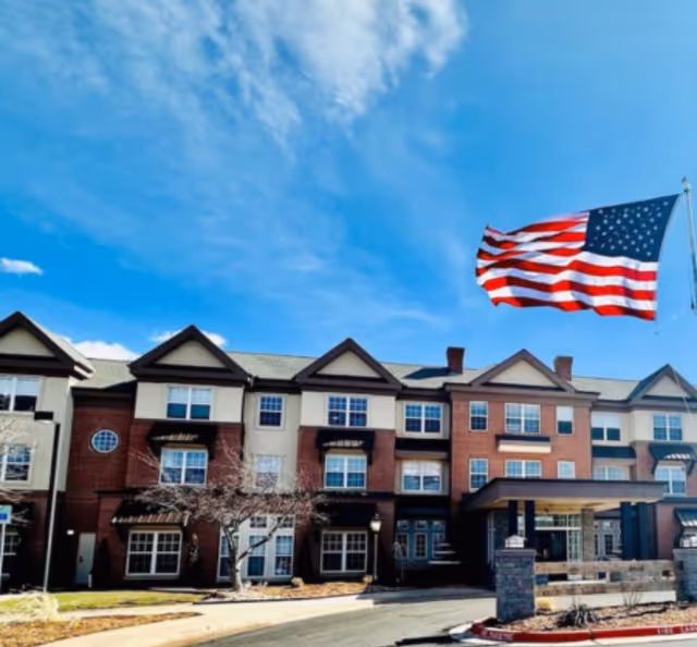 Front facade of Saddlebrook Senior Living, a multi-story building with a waving American flag.