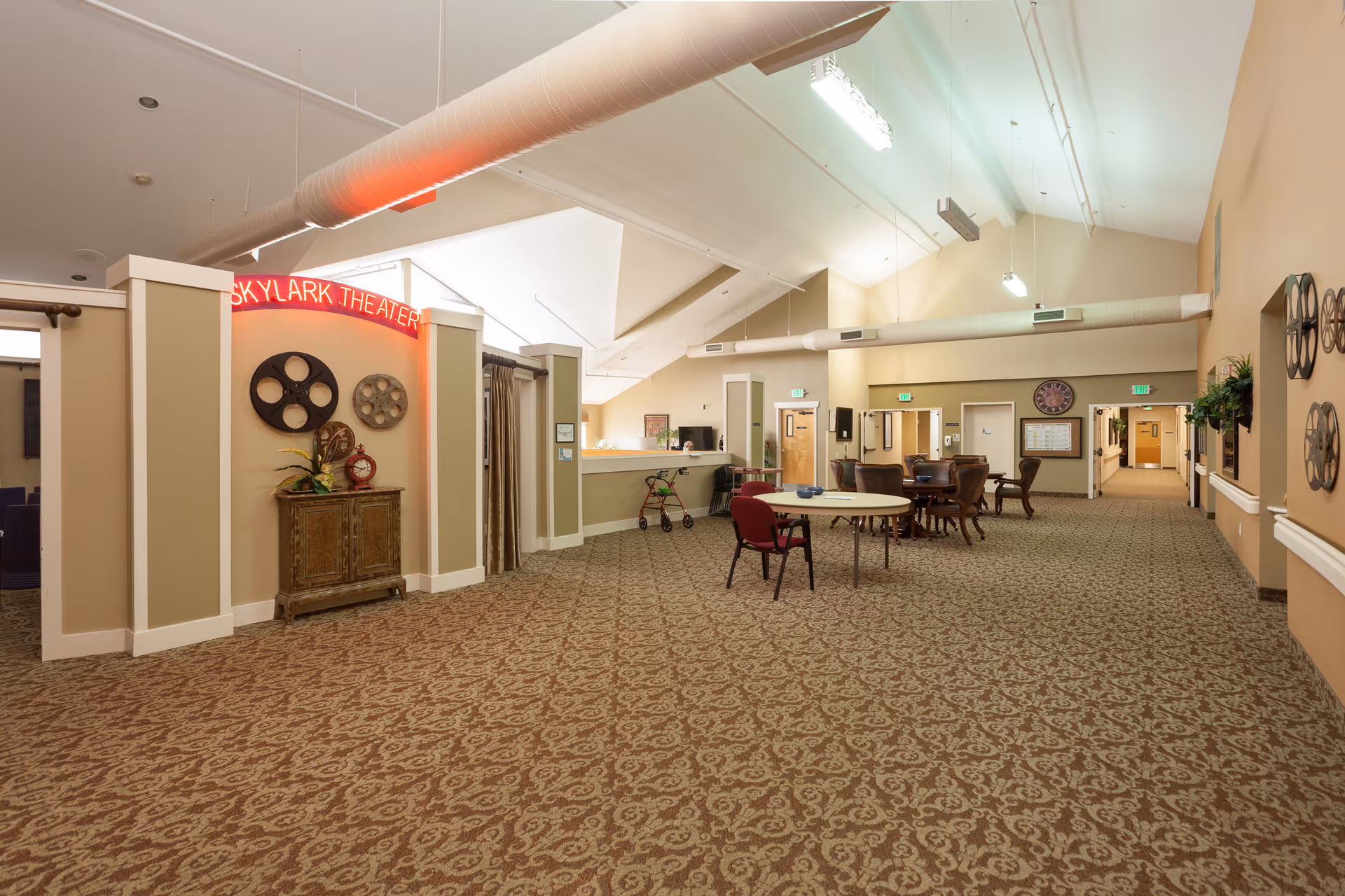 Interior lobby of Skylark Assisted Living with theater signage, reception desk, and clustered tables