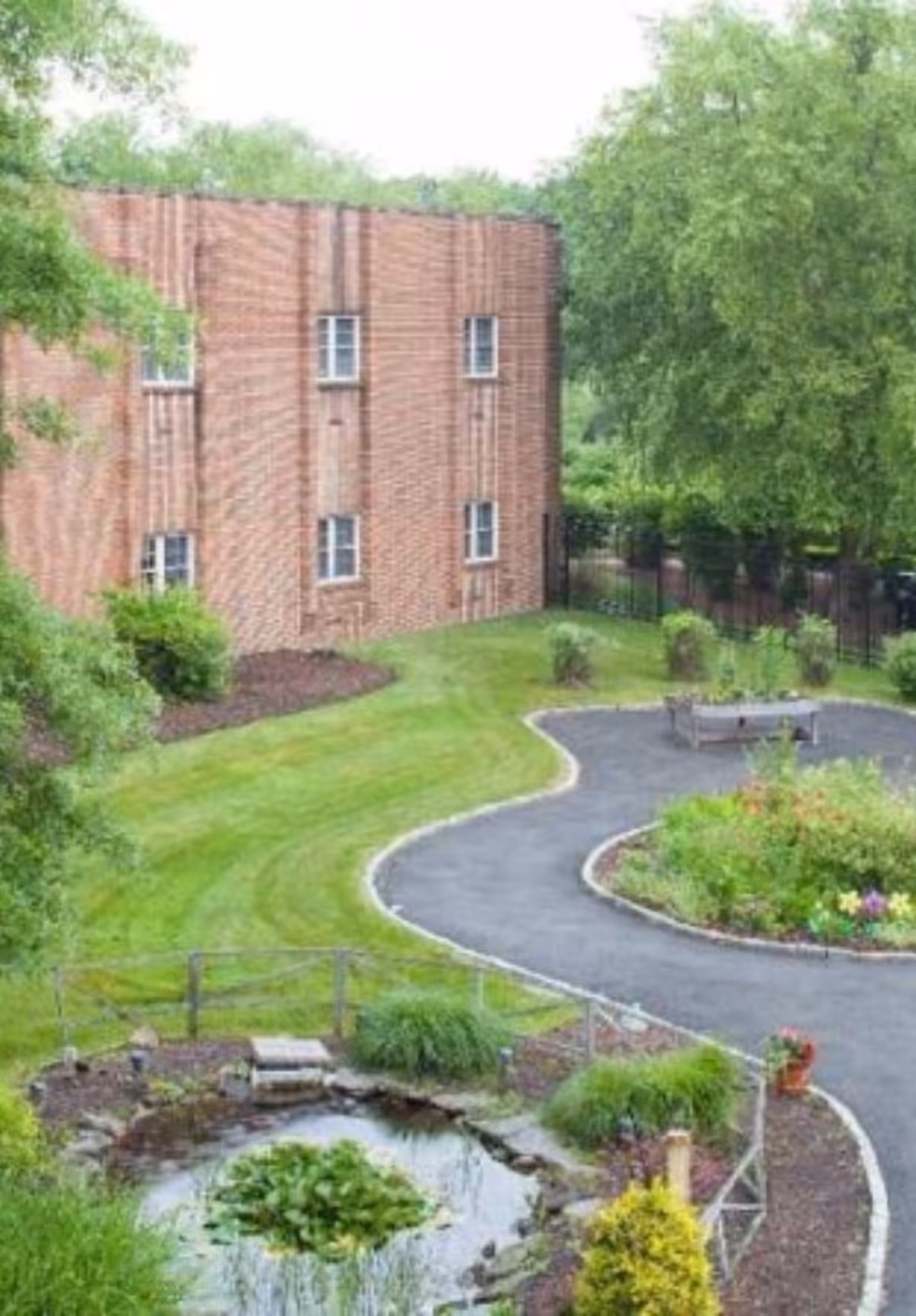 Exterior view of Saint John Paul II Center with brick building, lawns, curved path, and pond.