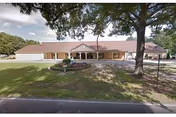 Single-story brick senior living facility with a shaded entrance and well-kept lawn.