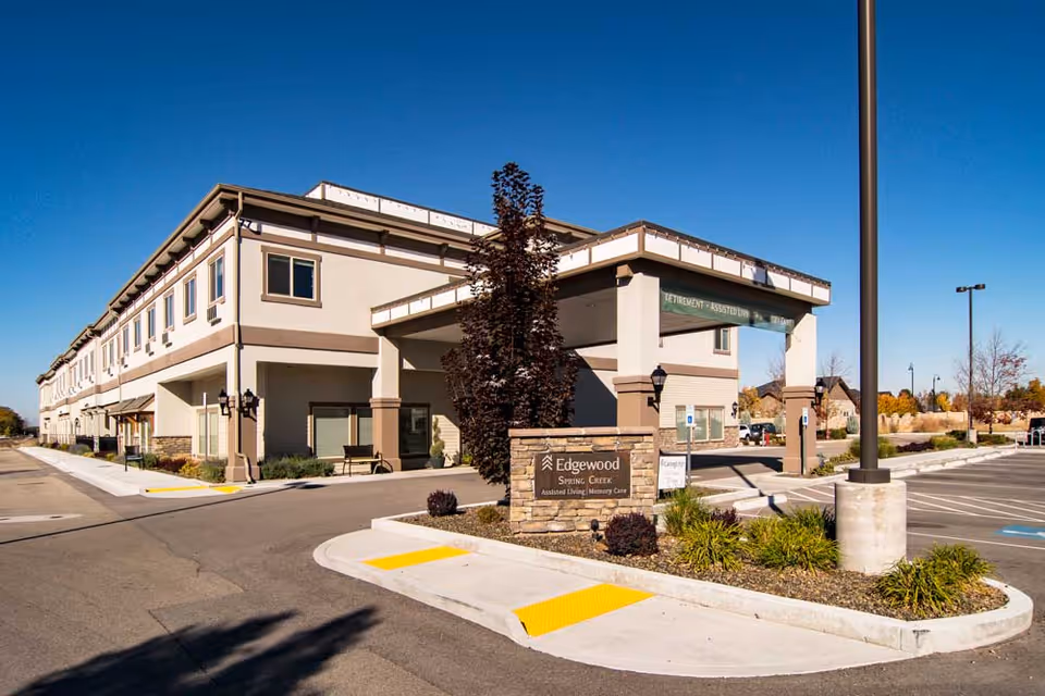 Exterior front entrance of Edgewood Spring Creek assisted living facility with a porte-cochere, sign, and adjacent parking area.