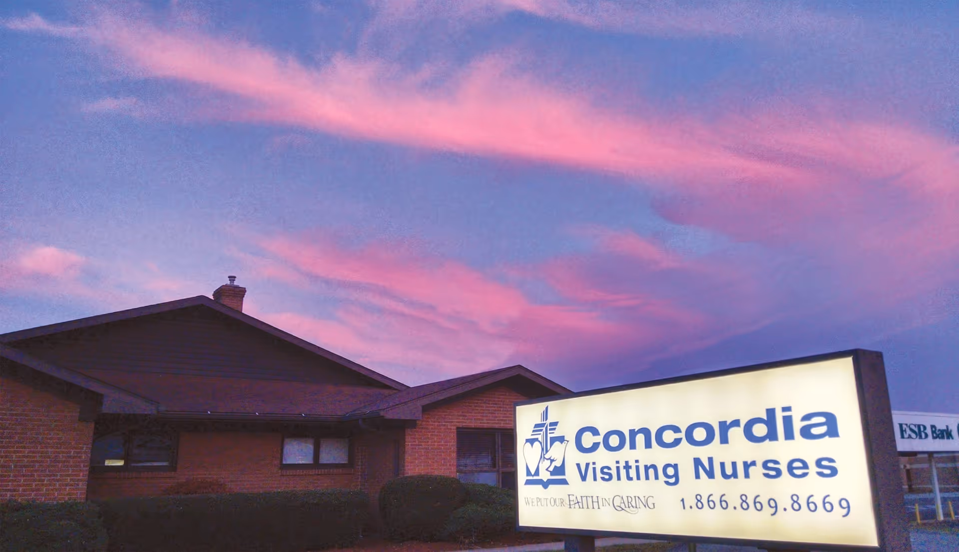Exterior view of Concordia Visiting Nurses Baden Branch building with illuminated sign at dusk.