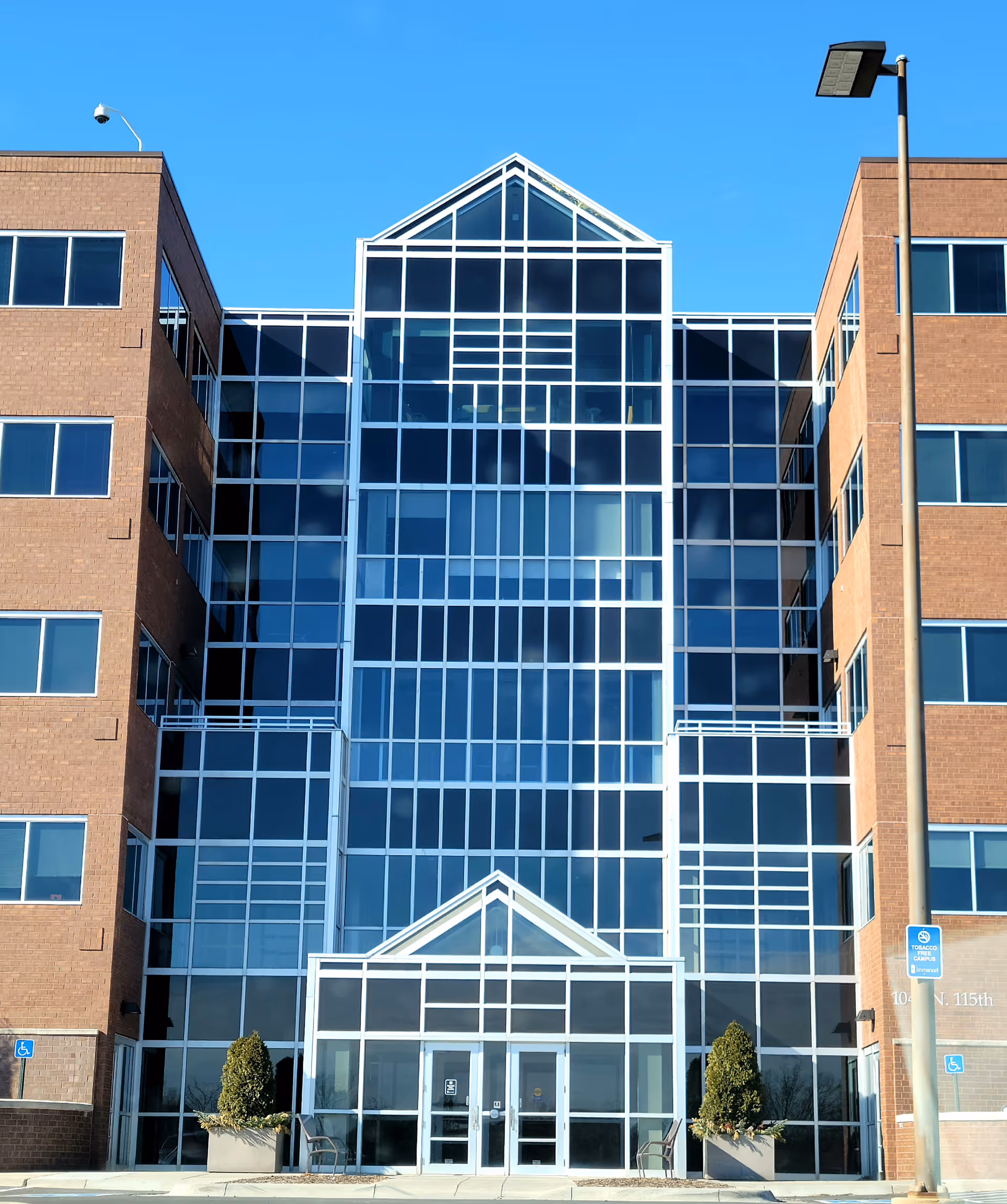 Front view of a modern glass-front building with brick wings and a glass entrance.