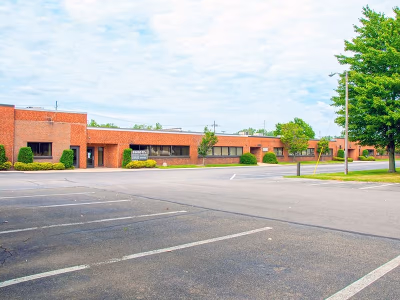 Brick, single-story senior care building with parking lot and trimmed shrubs.