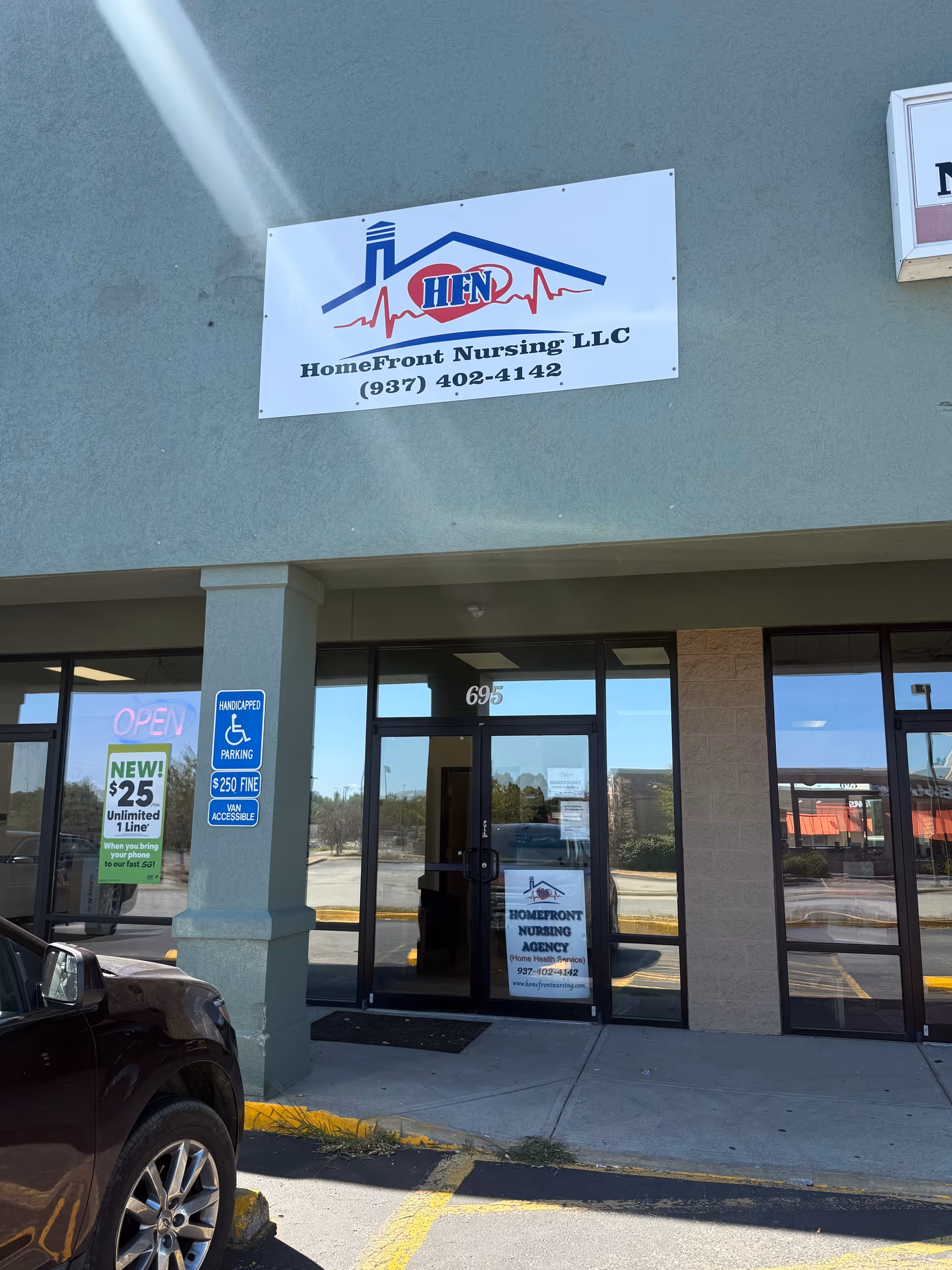 Exterior view of HomeFront Nursing LLC with glass entrance doors and a parked car.