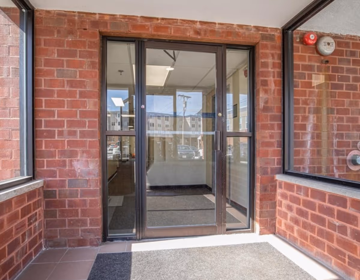 Glass double doors framed by red brick exterior lead to a lobby entrance