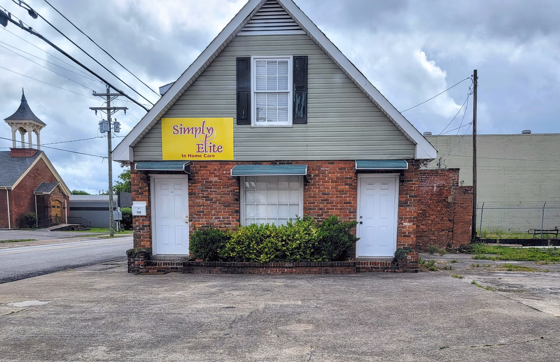 Small brick building with Simply Elite In Home Care sign in front.