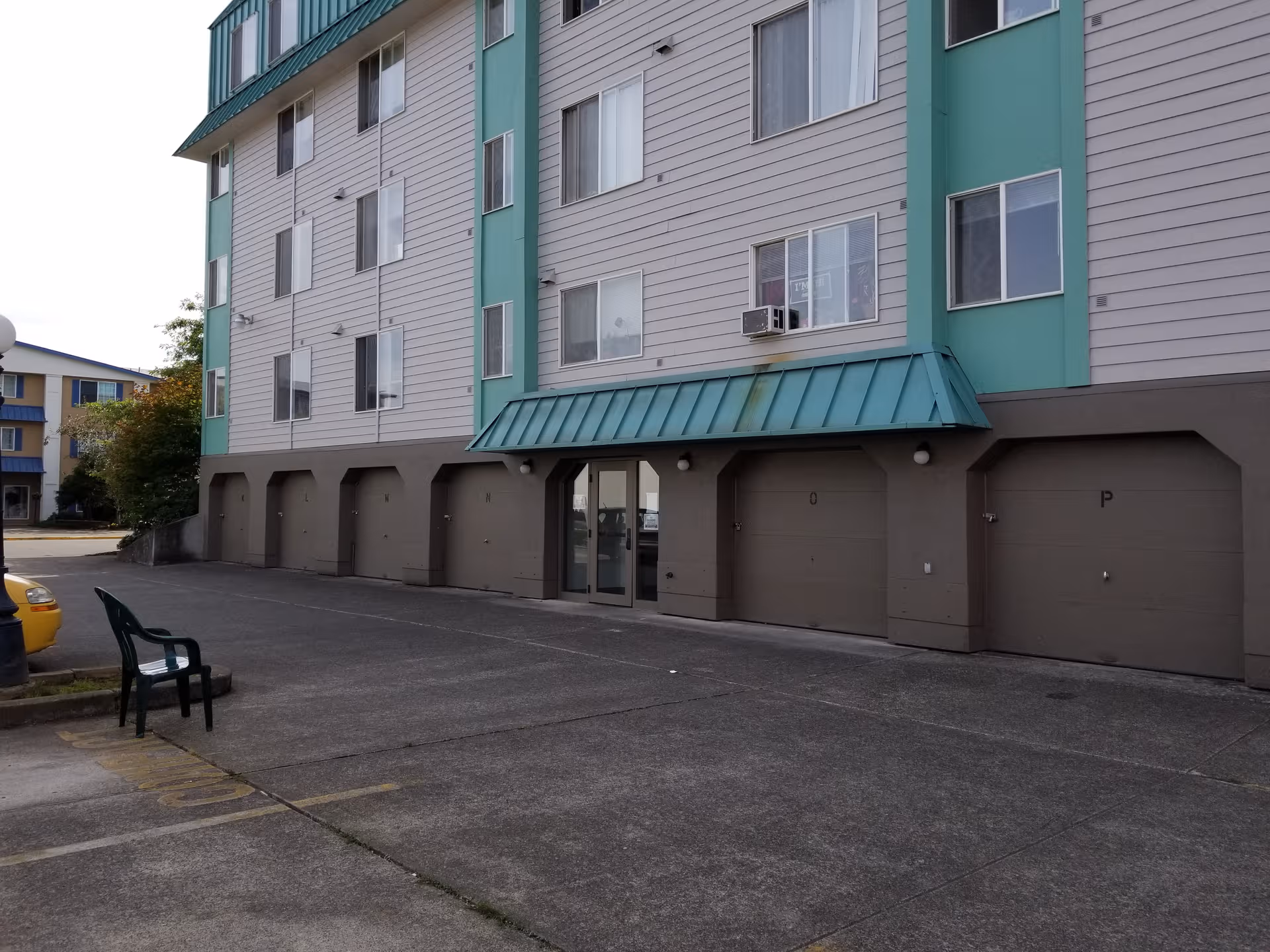 Exterior view of a multi-story senior living building with a front entrance and garage bays.
