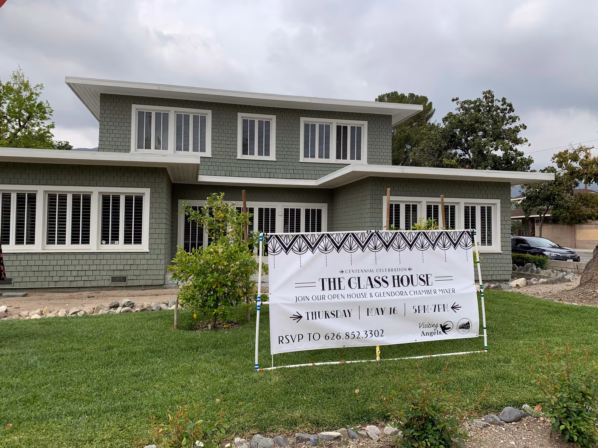 Grey exterior building with a lawn banner promoting an open house event.