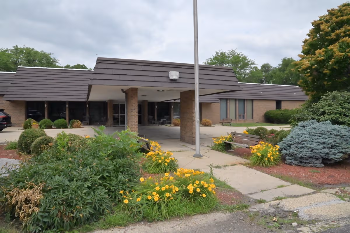 Brick building entrance of Goldwater Care Peoria Heights with landscaped shrubs.