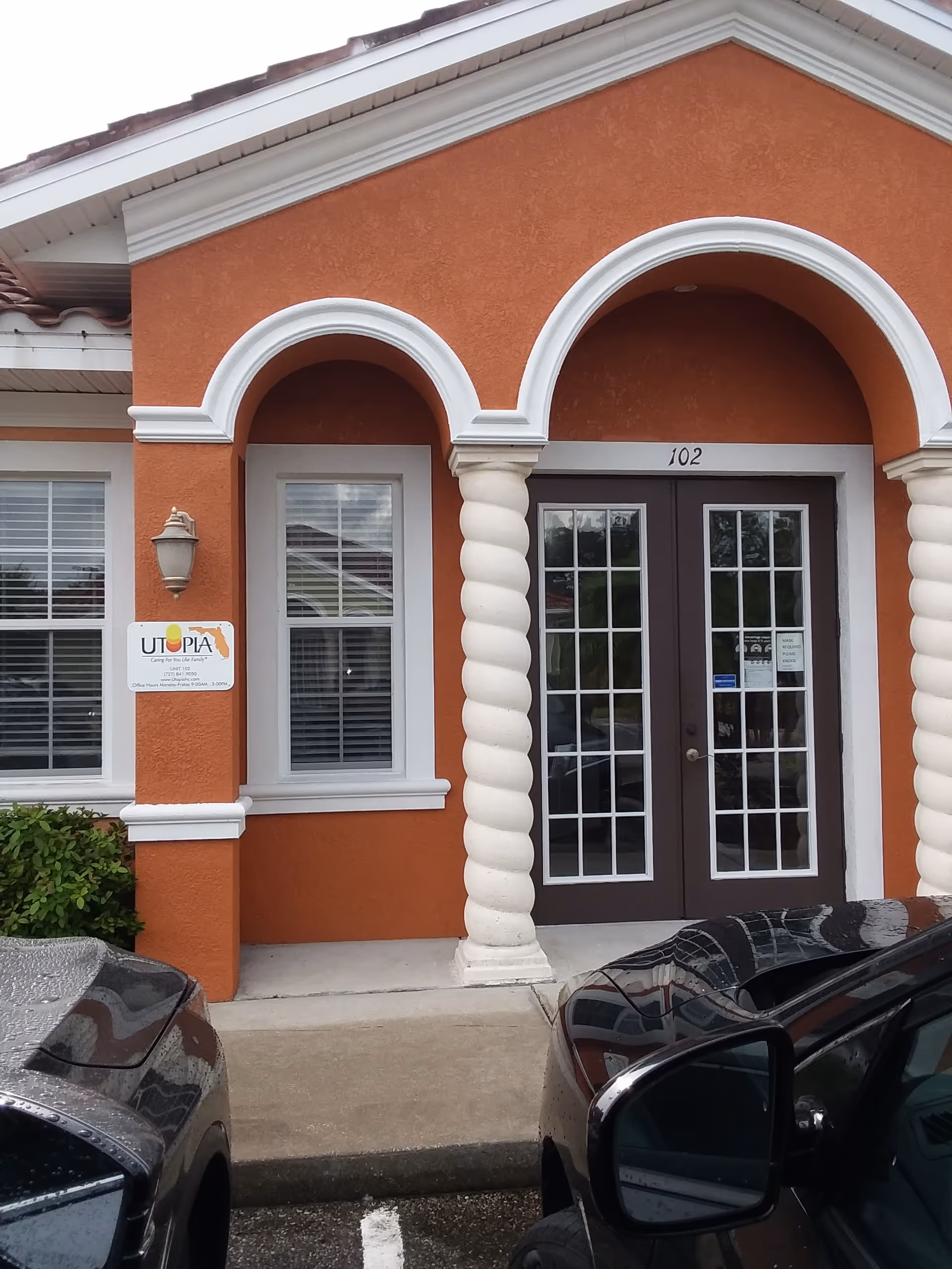 Orange building entrance with arched white trim, twisted columns, and glass-paneled double doors.