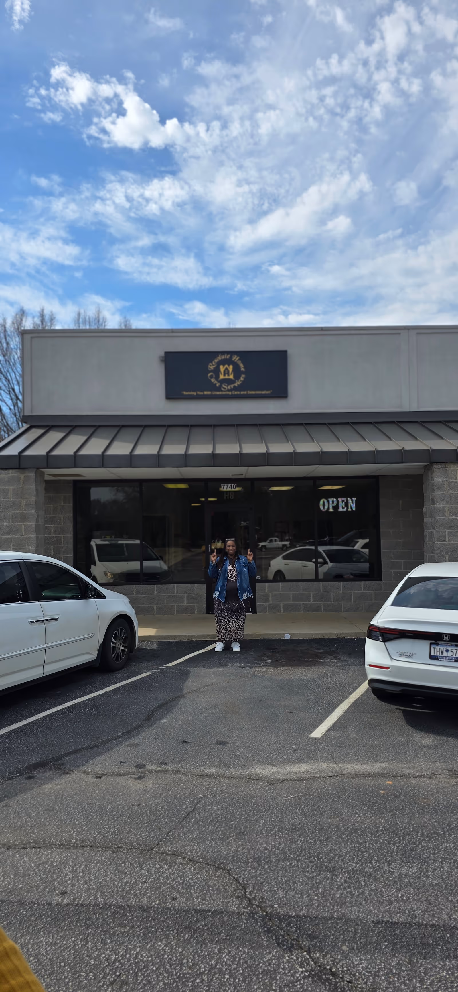 Two people stand at the open entrance of a storefront senior care facility.
