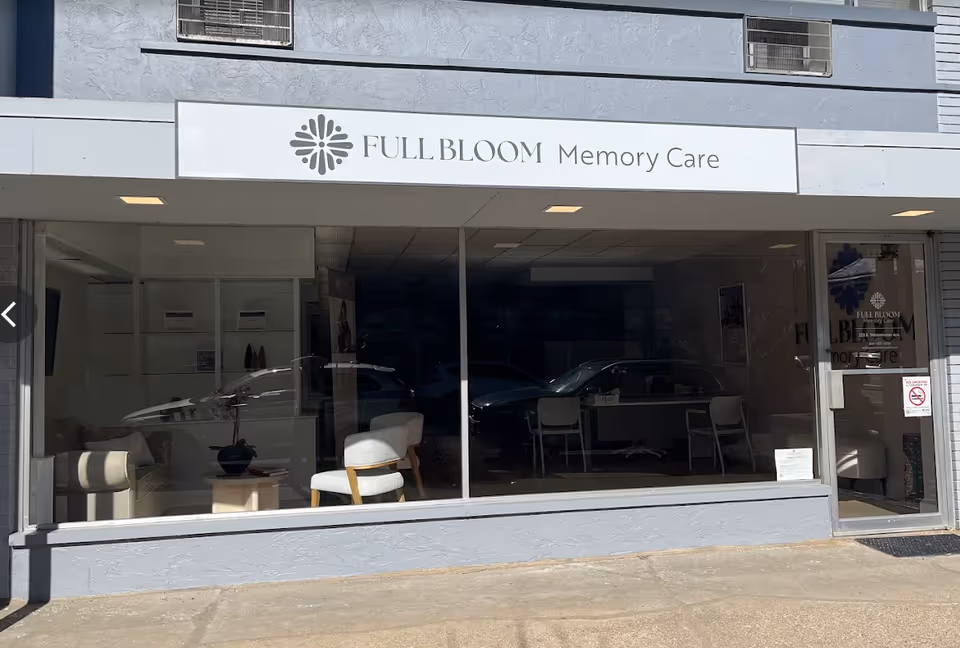 Exterior storefront of Full Bloom Memory Care with glass windows and interior seating.