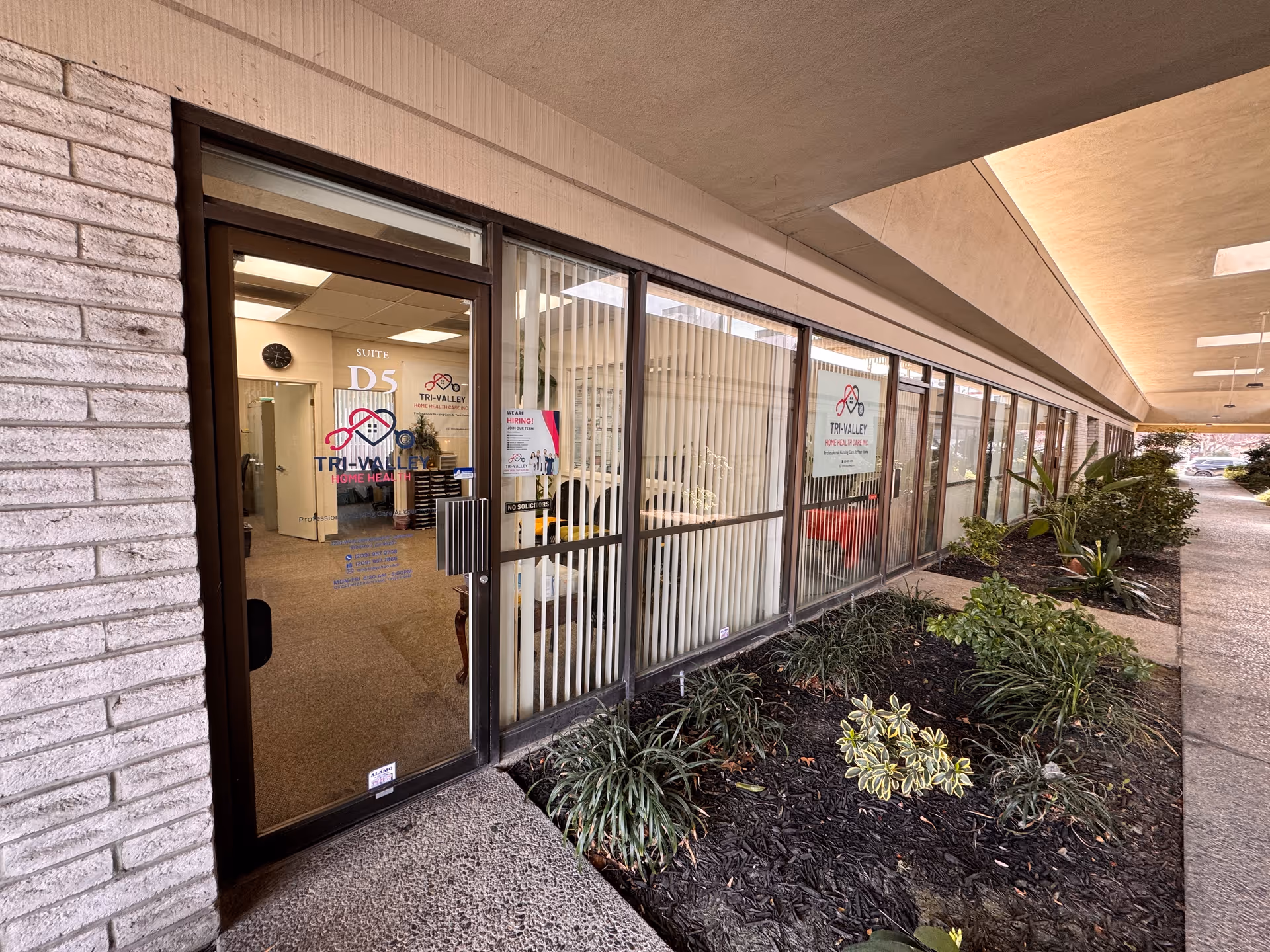 Exterior view of Tri-Valley Home Health Care entrance with glass doors and landscaping.