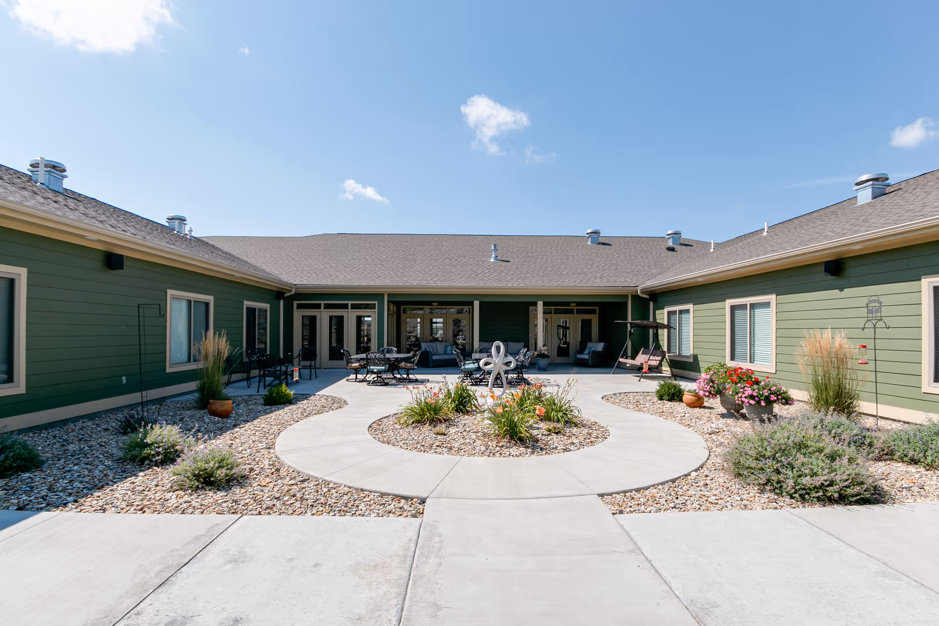 Green, single-story facility with a circular courtyard and outdoor seating area.