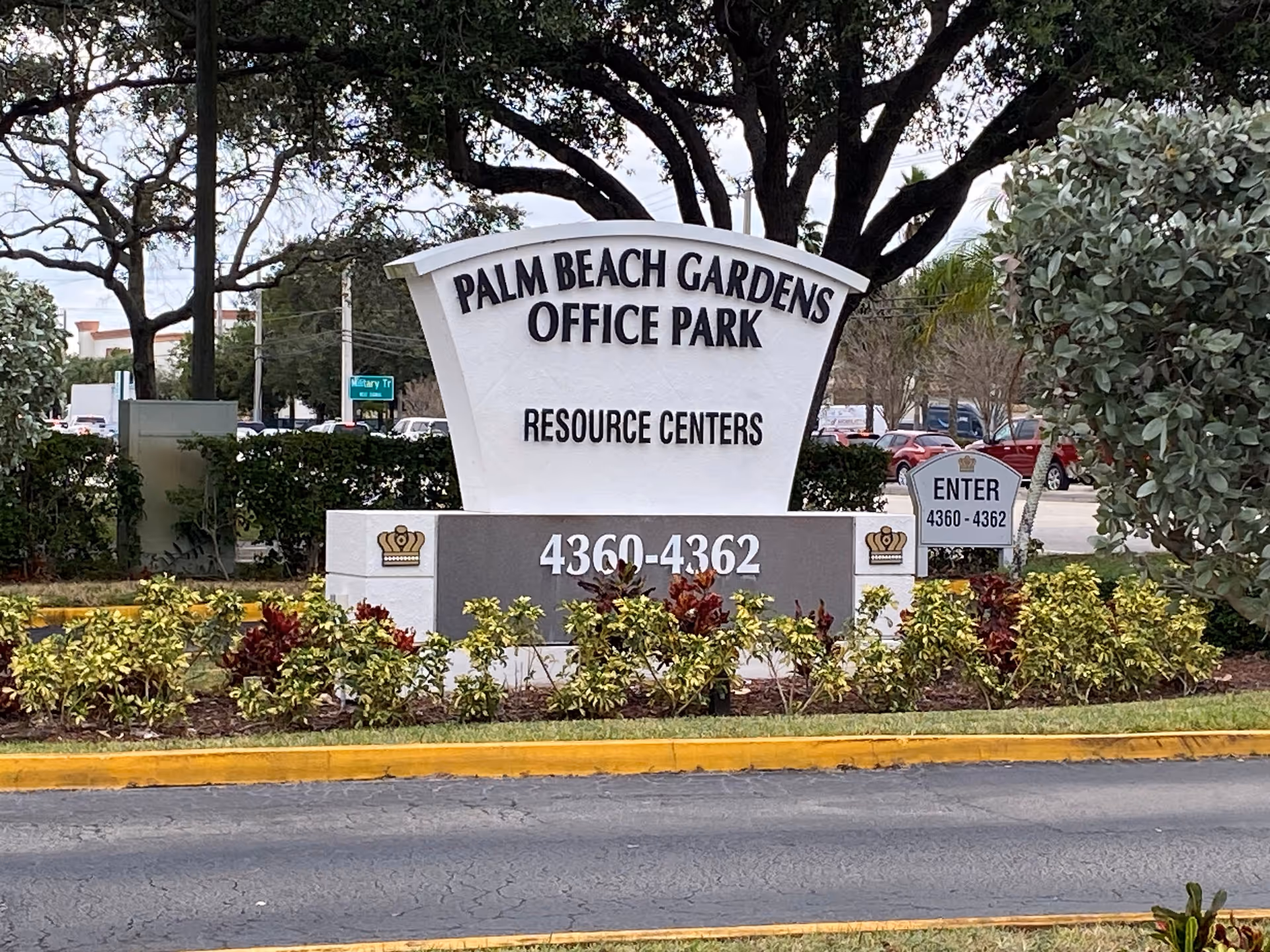 Outdoor sign for Palm Beach Gardens Office Park with surrounding shrubs and roadway.
