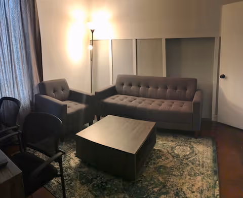 A small lounge area in a senior living facility with sofas, chairs, and a coffee table.