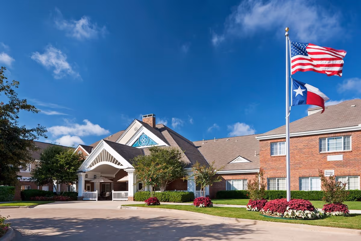 Front exterior of Monarch at Richardson with brick building, entrance arch, and flagpoles.