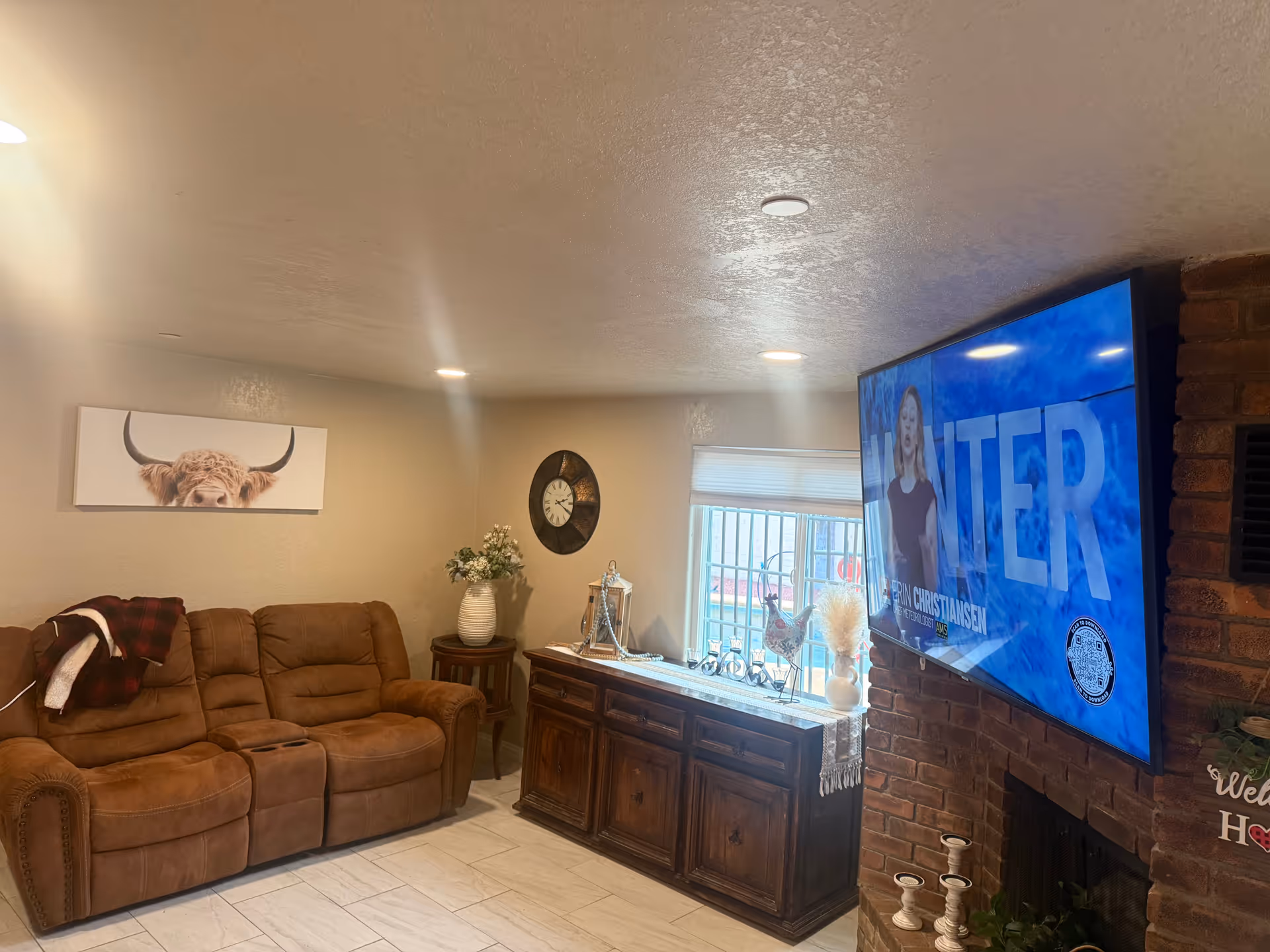 Cozy living room with brown sectional, wooden cabinet, and wall-mounted TV.