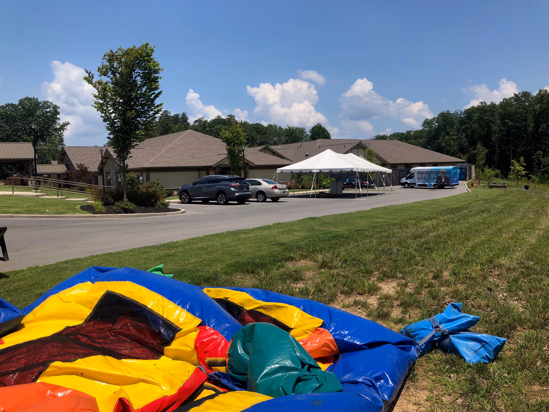 Exterior view of Thrive at Brow Wood with a white canopy tent and parked cars.