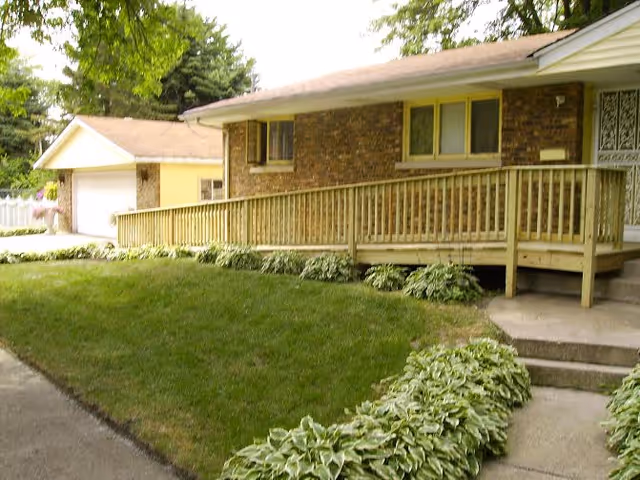 Exterior view of a brick senior living facility with a wooden ramp and lawn.