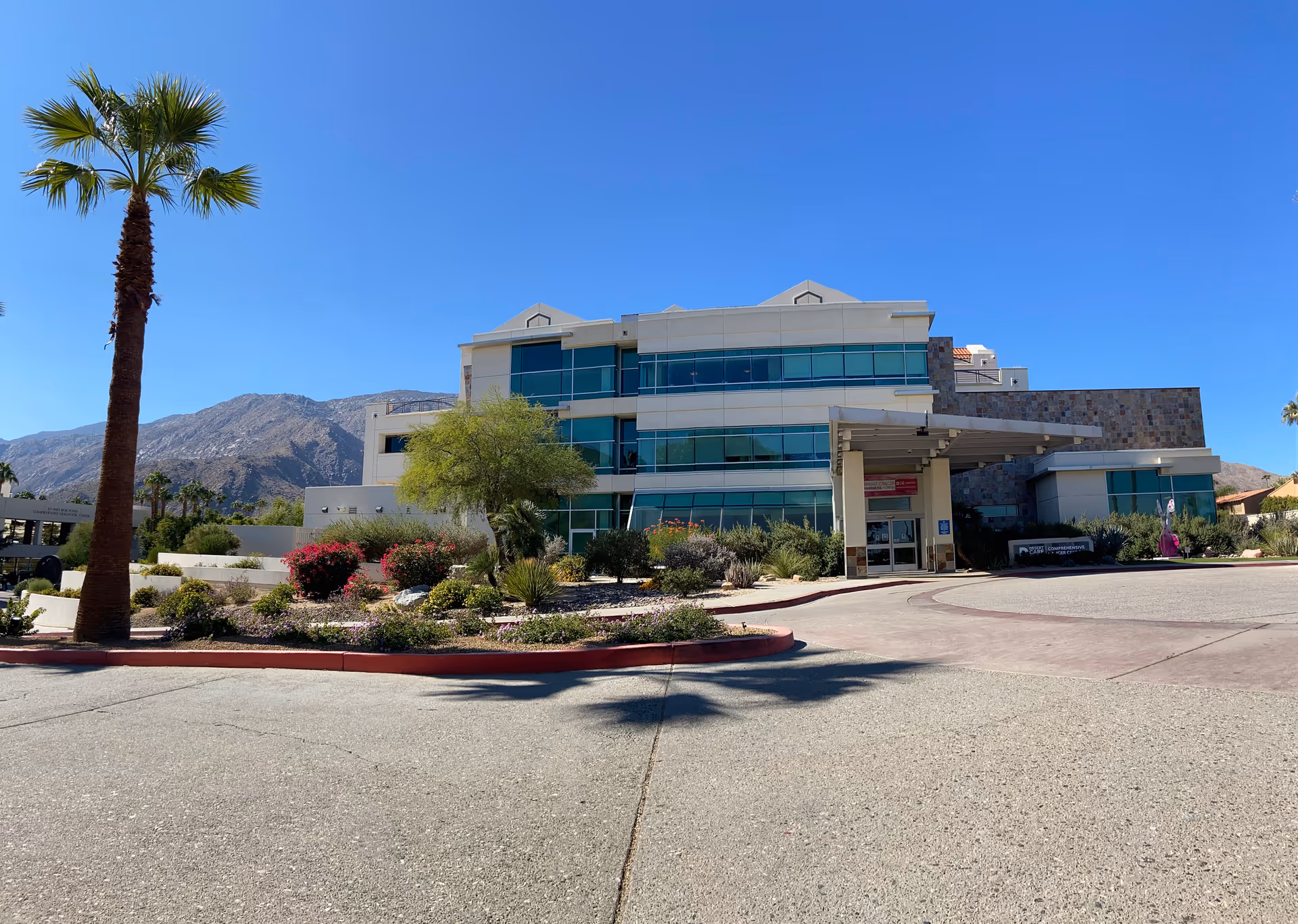 Desert Regional Medical Center building with glass windows and landscaped entrance under a clear blue sky.