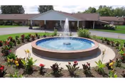Circular fountain with flower beds in front of Ellen Memorial Health Care Center.