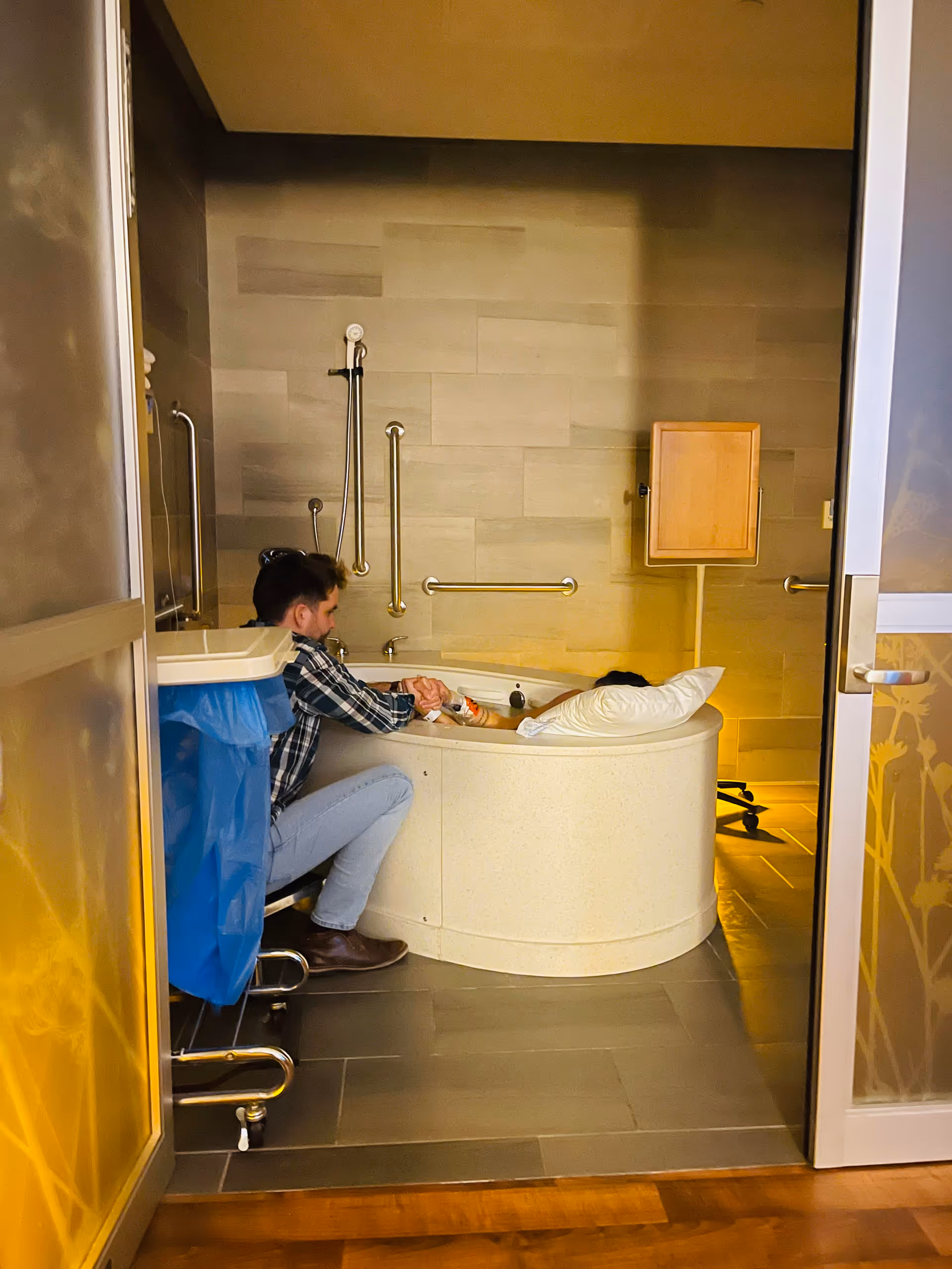 Caregiver assists a resident in a large, accessible bathroom with grab bars and a tub