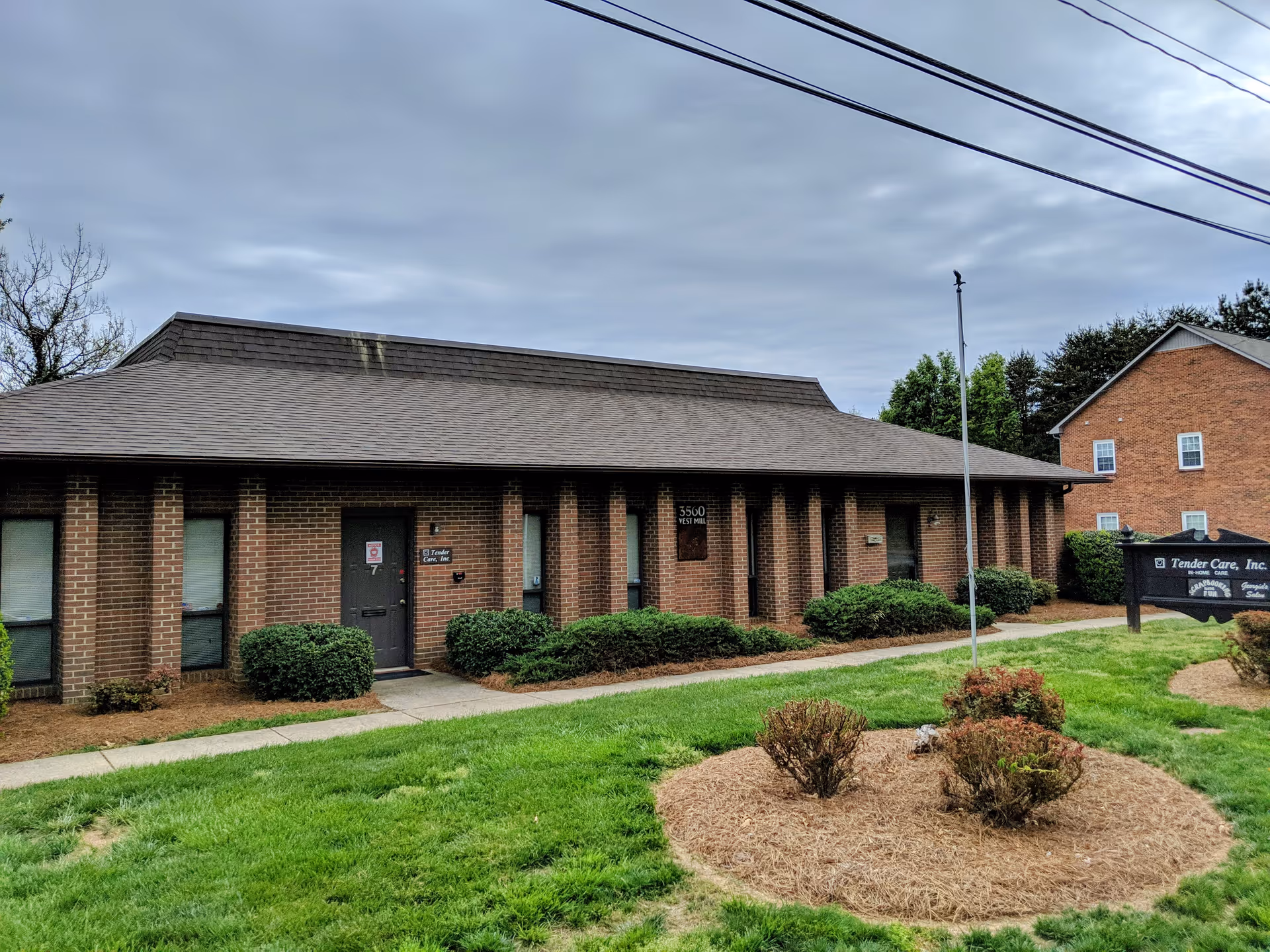 A single-story brick senior care facility exterior with shrubs and a Tender Care, Inc. sign.