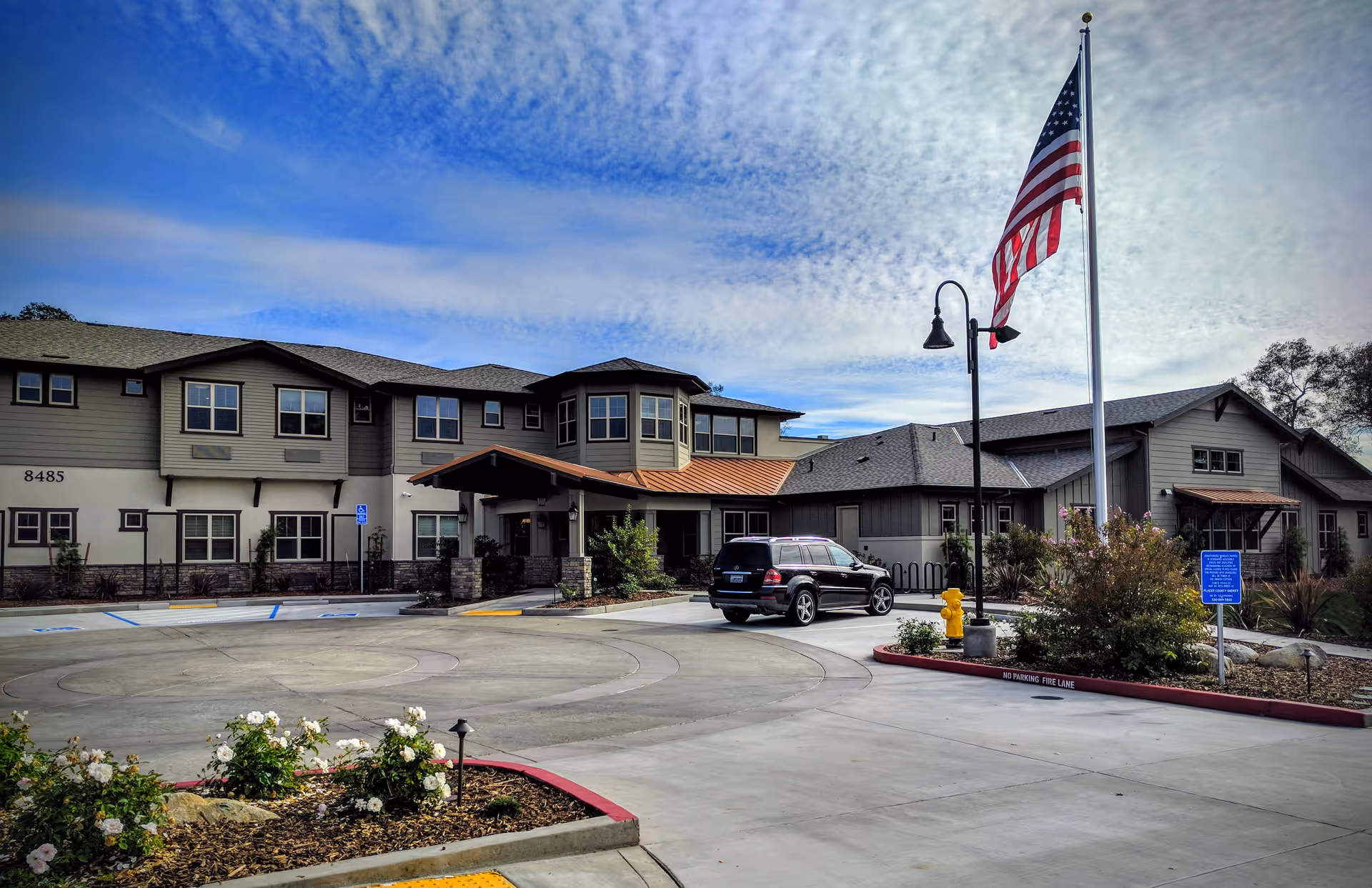 Exterior view of CountryHouse at Granite Bay with entrance, parking lot, and American flag in front.