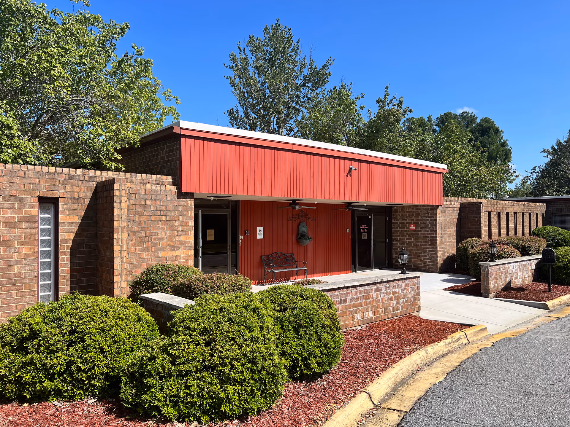 Brick exterior of River Towne Center with red entrance canopy and landscaped shrubs.