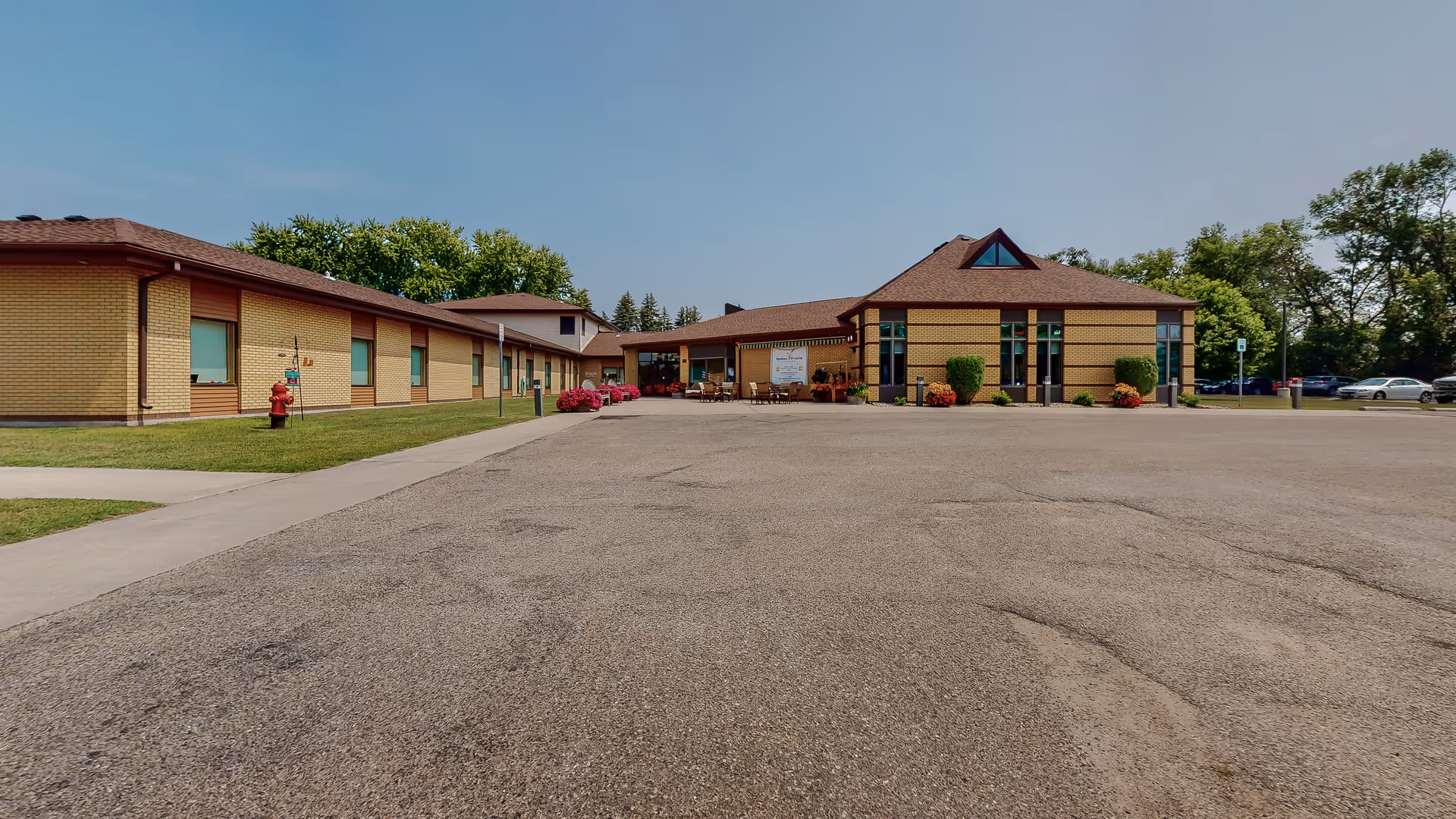 Hatton Prairie Village exterior: a long brick building with central entrance and wide parking lot.