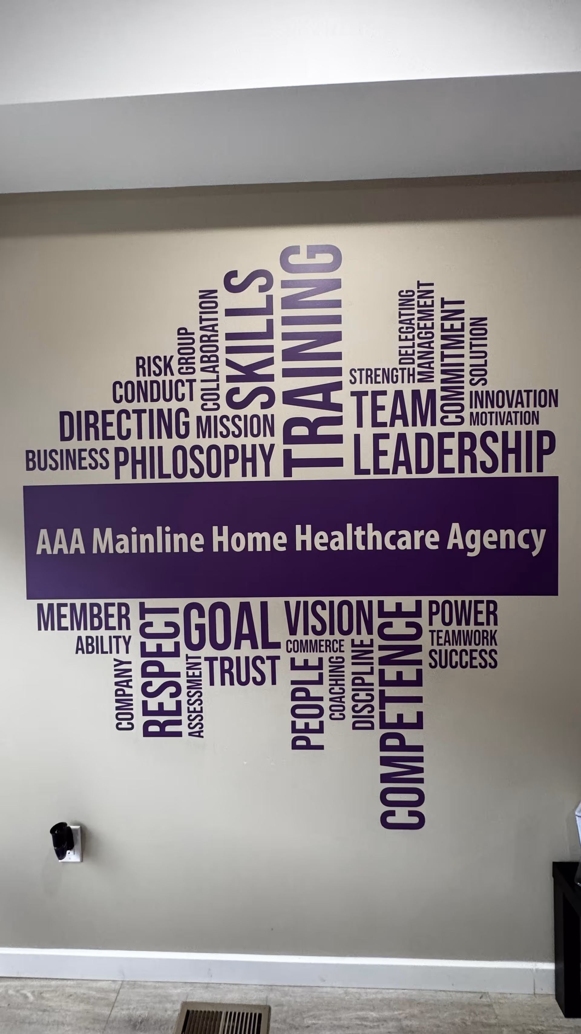 Interior wall featuring a large purple word cloud and banner reading AAA Mainline Home Healthcare Agency