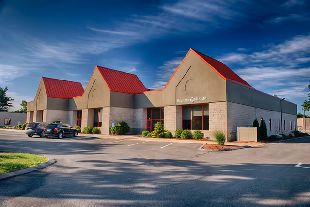 Exterior view of Baystate Home Health in West Springfield, with a red-roofed building and parked cars.