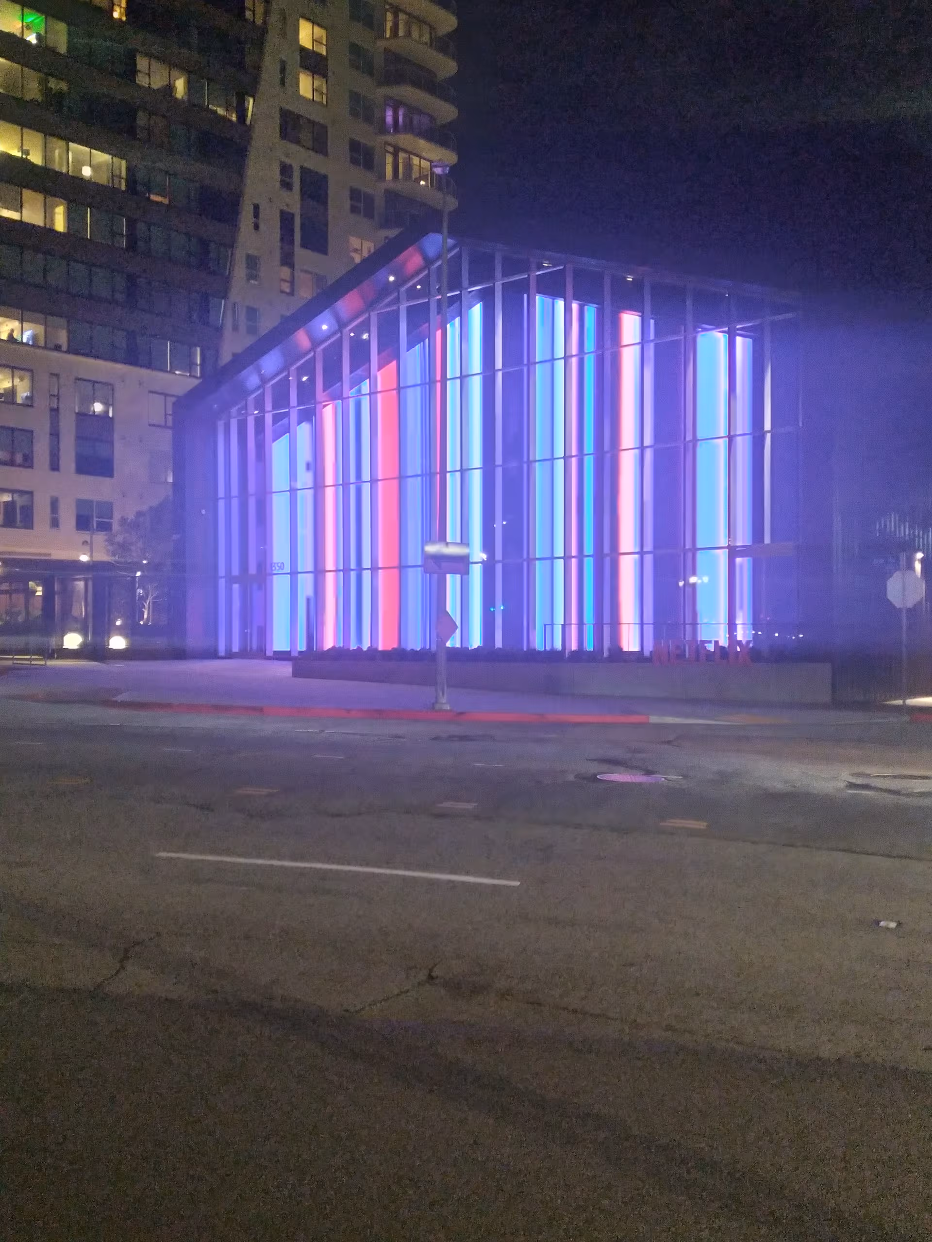 Night exterior of a modern building with colorful vertical neon lights.