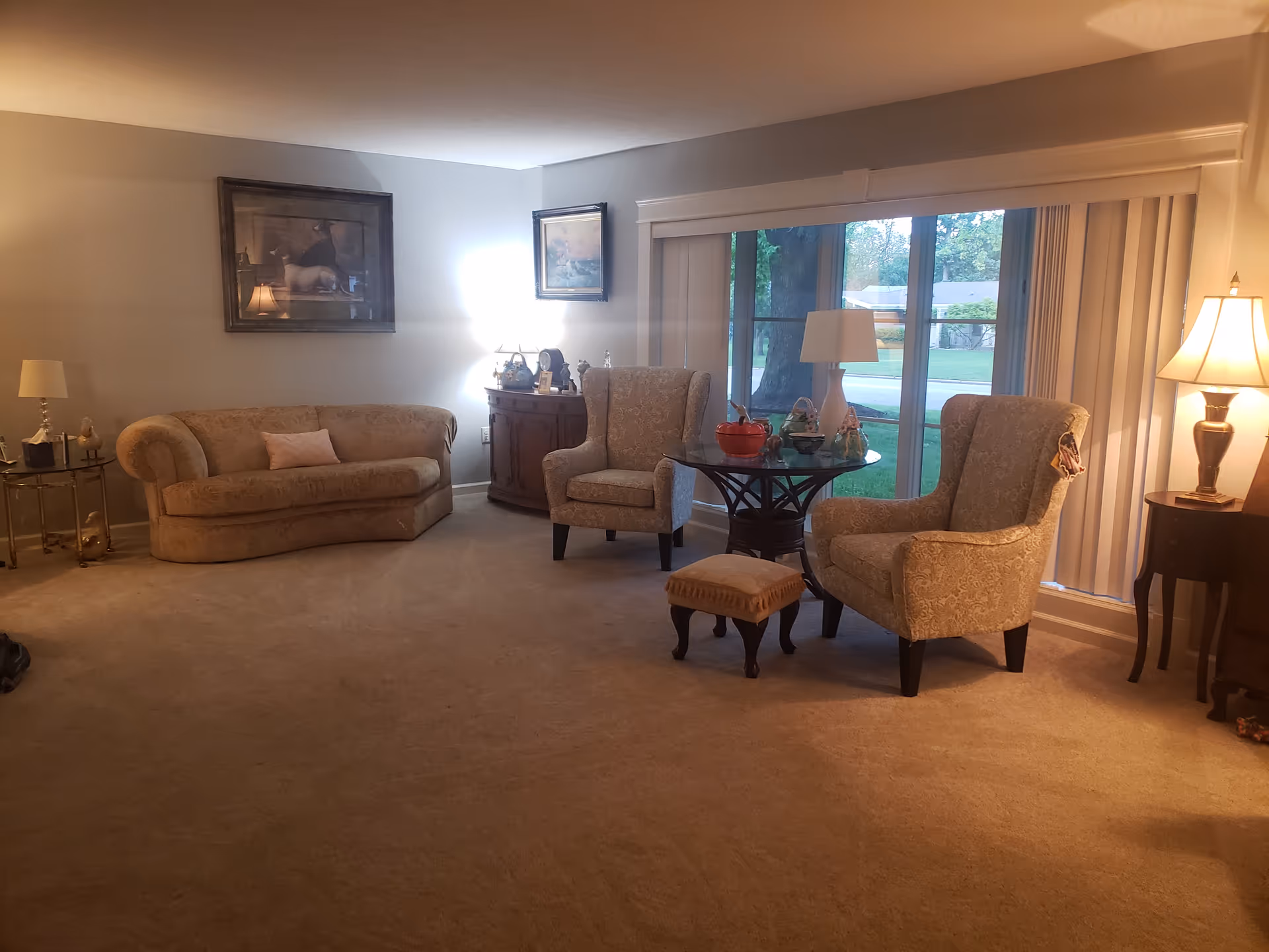 Cozy living room with sofa, armchairs, coffee table, and sliding glass doors.