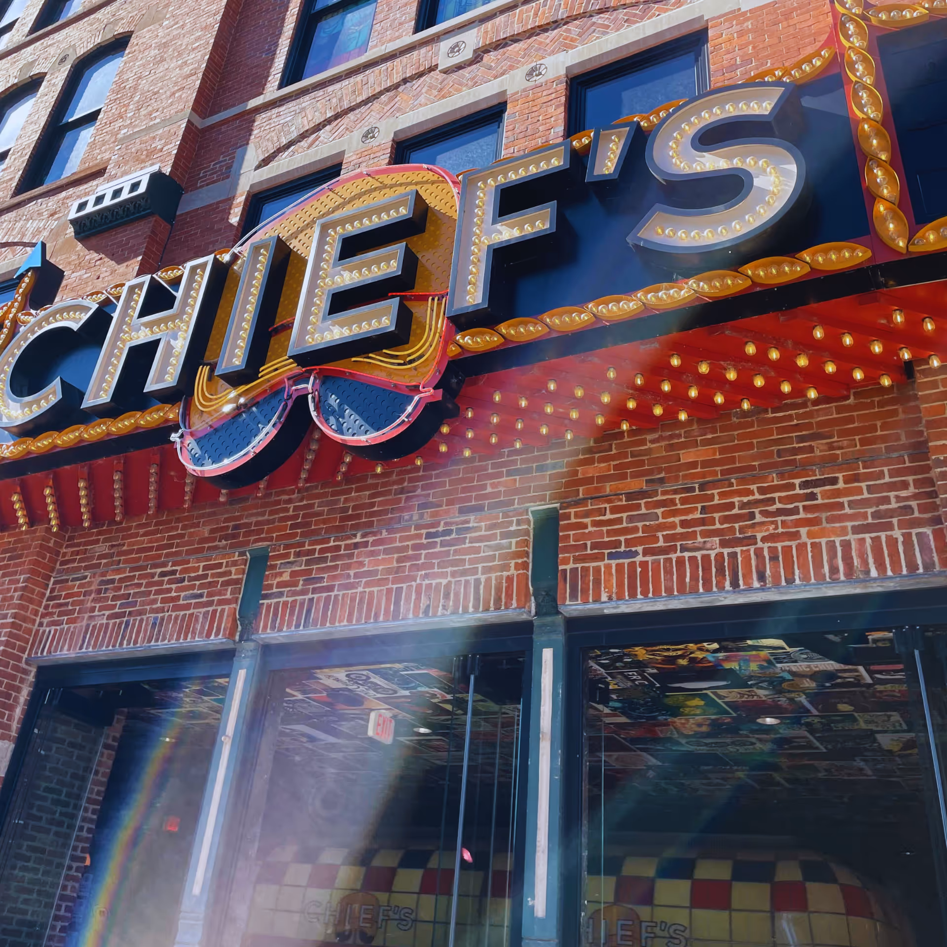 A brick storefront with a large illuminated CHEFS sign and glass entry.