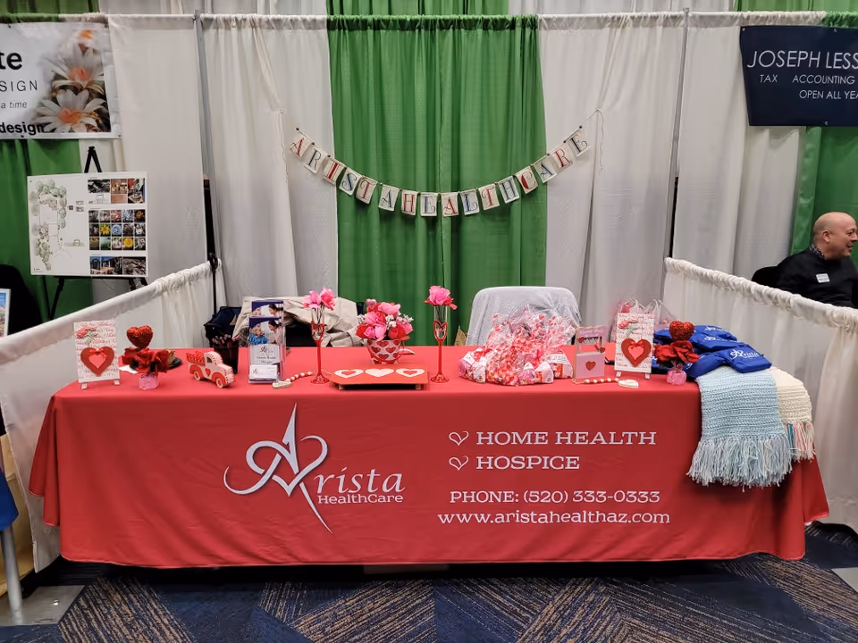 Convention booth for Arista HealthCare Hospice with a red tablecloth and Valentine decorations.