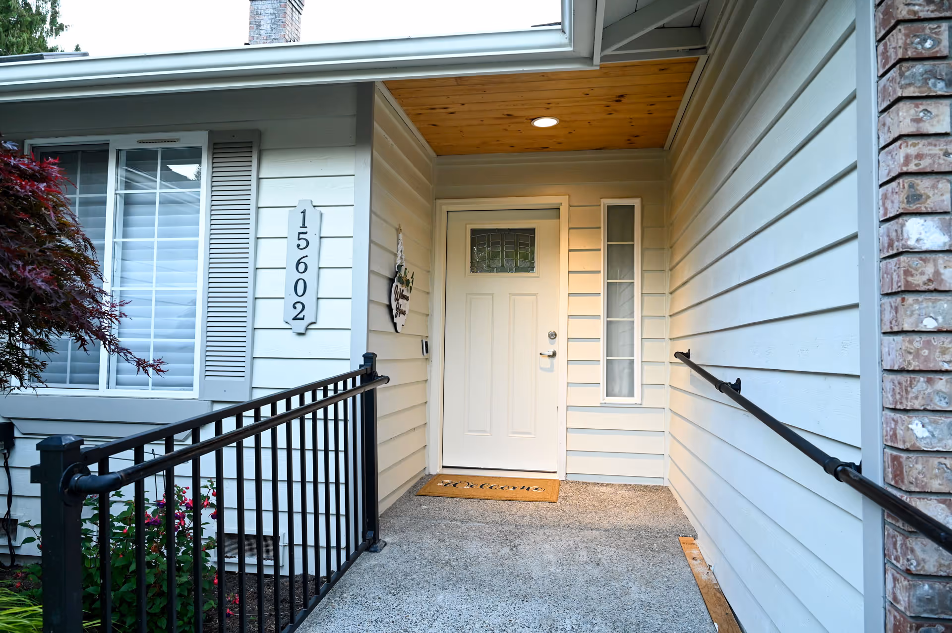 Front entrance of a beige residential building with a door and railing.