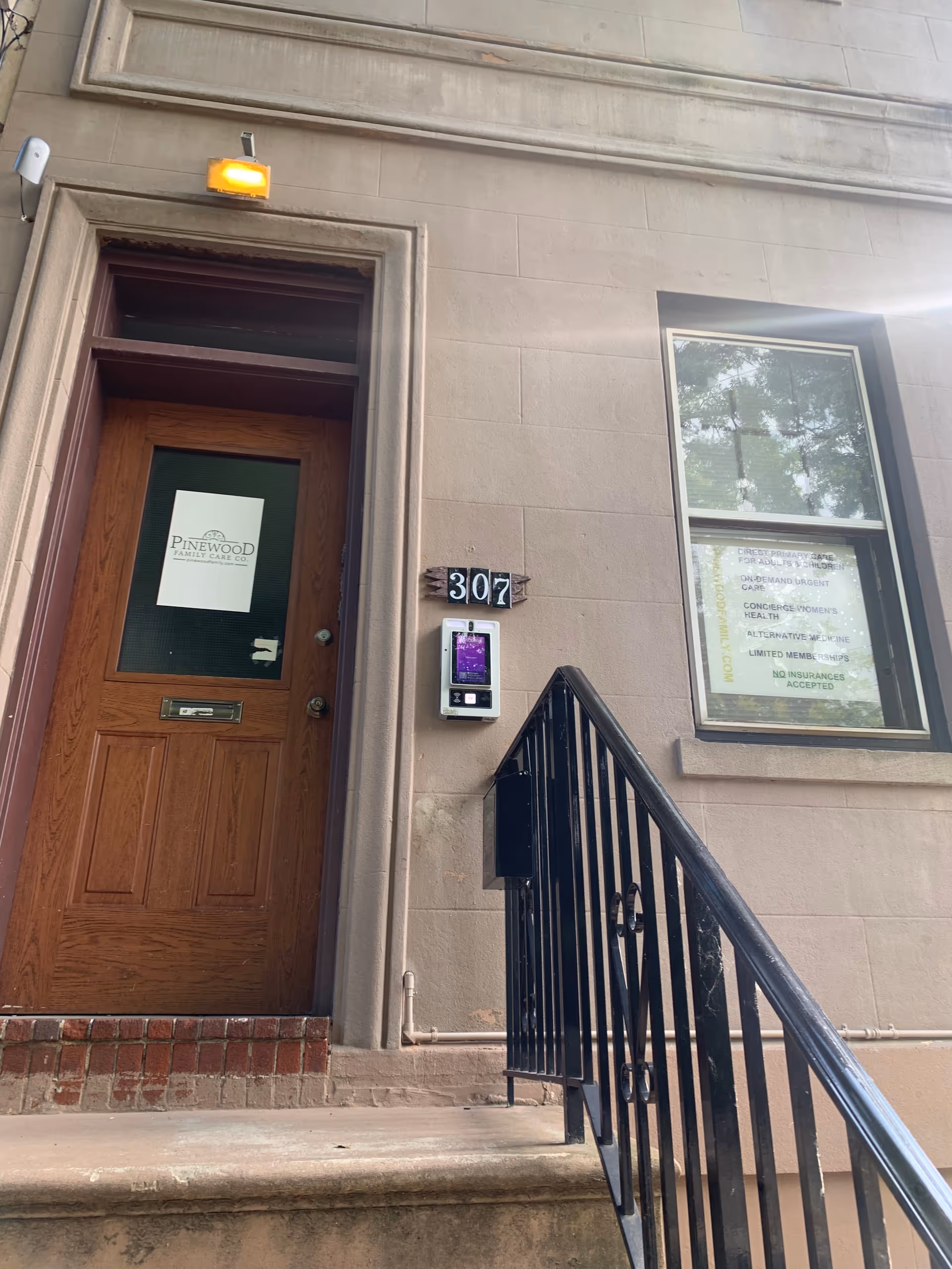 Exterior view of Pinewood Family Care entrance with wooden door, stairs, and railing.