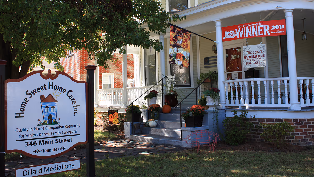 Front porch and sign of Home Sweet Home Care with pumpkins and plants.