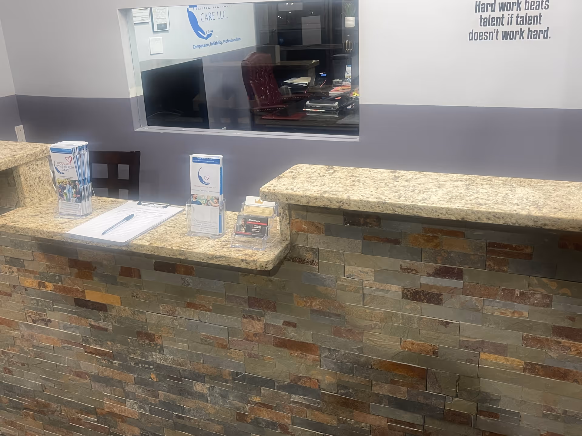 Reception desk with granite countertop, brochure stands, and a view into an office.