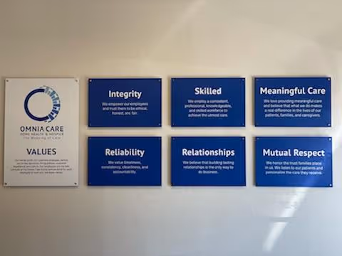 Wall displays blue values plaques and an OMNIACARE sign in a hallway.