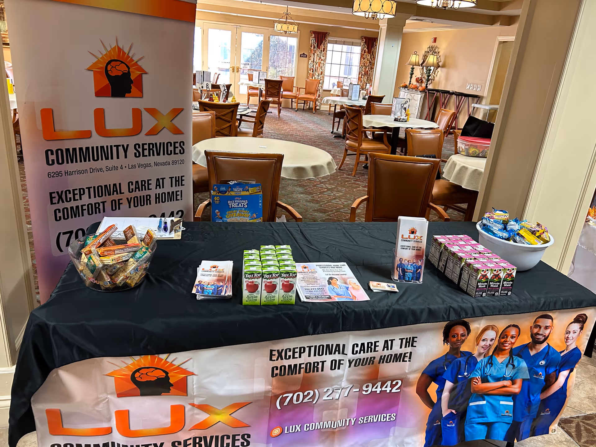 Promotional table with LUX Community Services banner in a senior living facility lobby.
