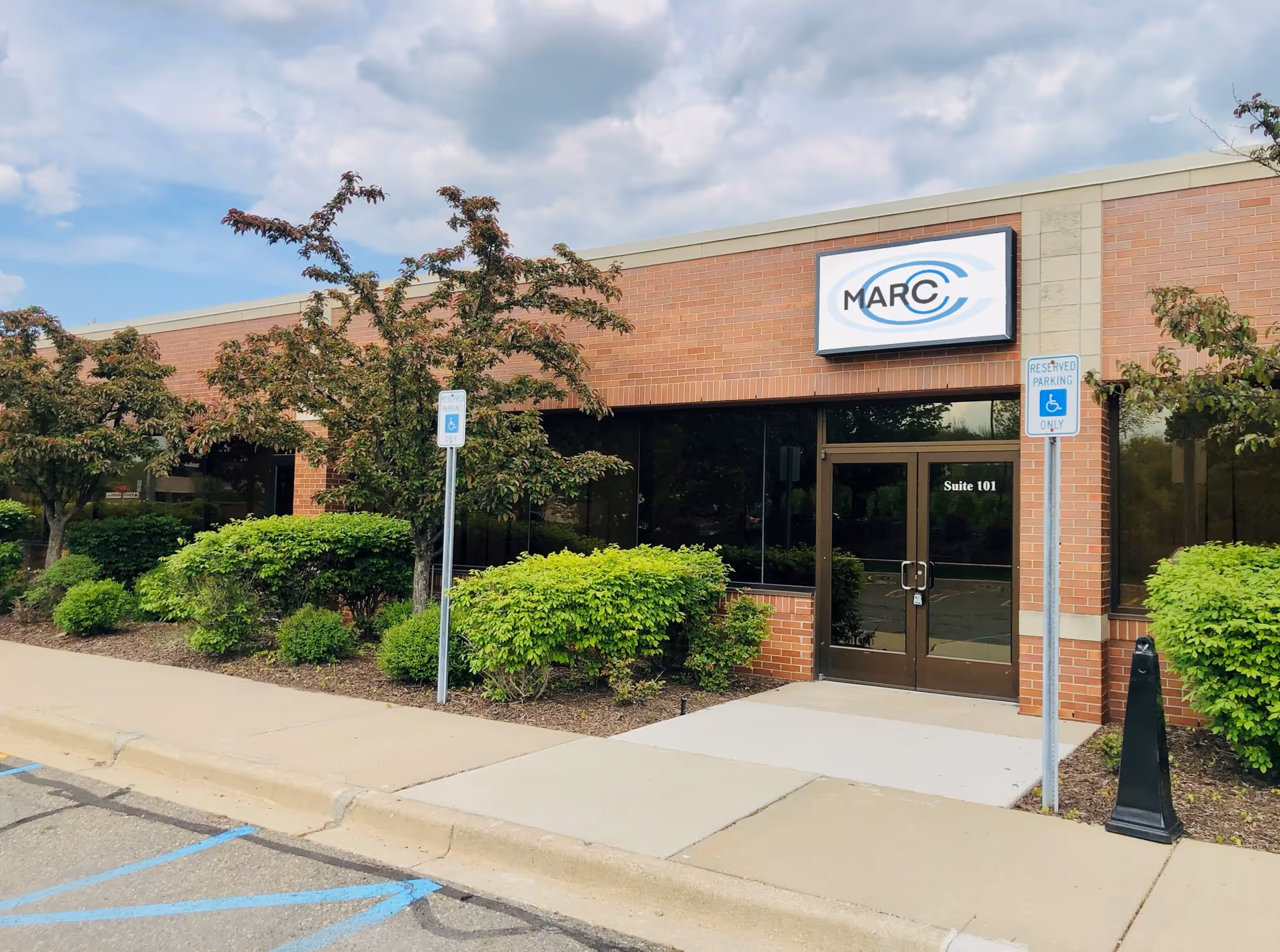 Brick building with MARC Therapies sign, glass entrance doors, and landscaped front.